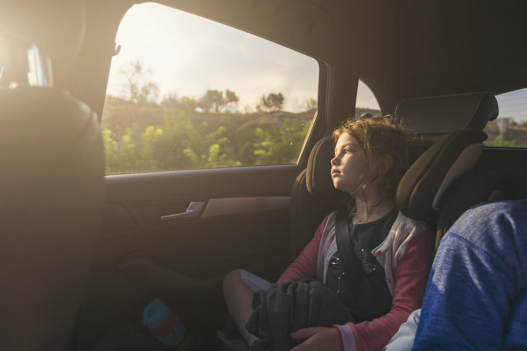 Kind sitzt im Auto und blickt aus dem Fenster